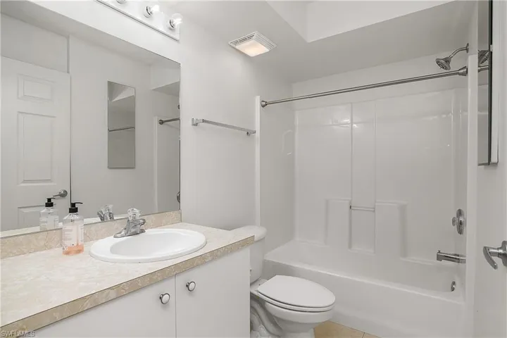 Bathroom featuring visible vents, toilet, vanity, and washtub / shower combination