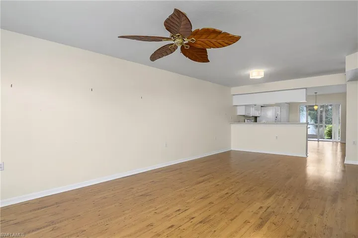 Unfurnished living room featuring light wood-style flooring, a ceiling fan, and baseboards