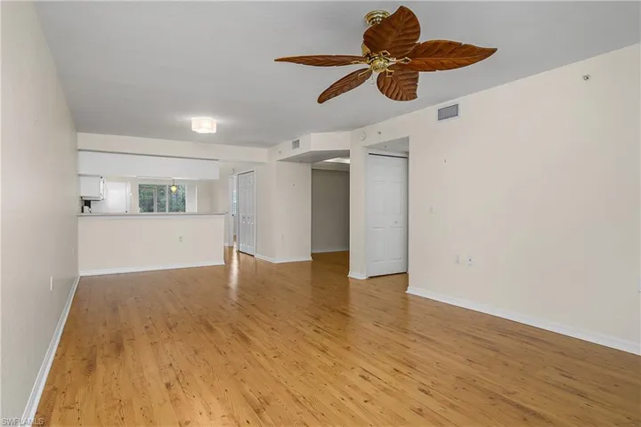 Unfurnished living room featuring light wood-style floors, visible vents, baseboards, and a ceiling fan