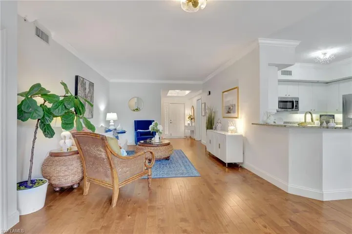 Living room with light wood-type flooring and crown molding