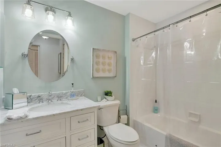 Full bathroom with toilet, vanity, and shower / bathtub combination with curtain