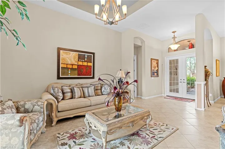 Living room featuring light tile patterned floors, french doors, and a chandelier
