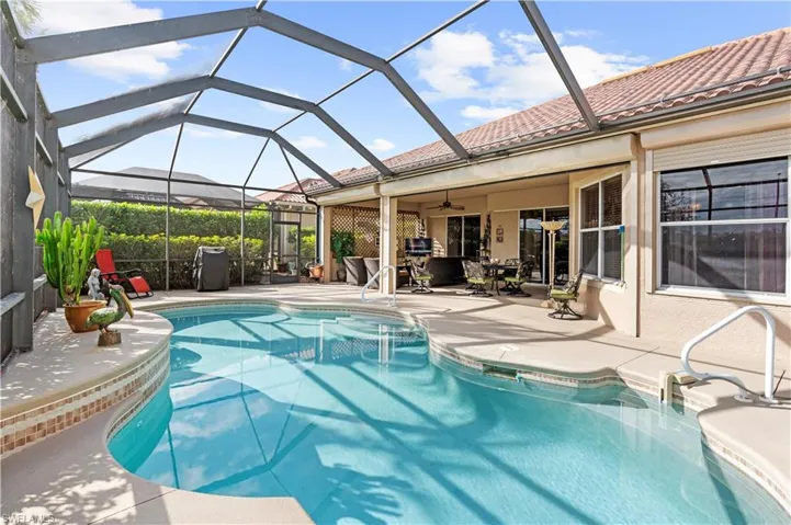 View of swimming pool with ceiling fan, glass enclosure, and a patio area