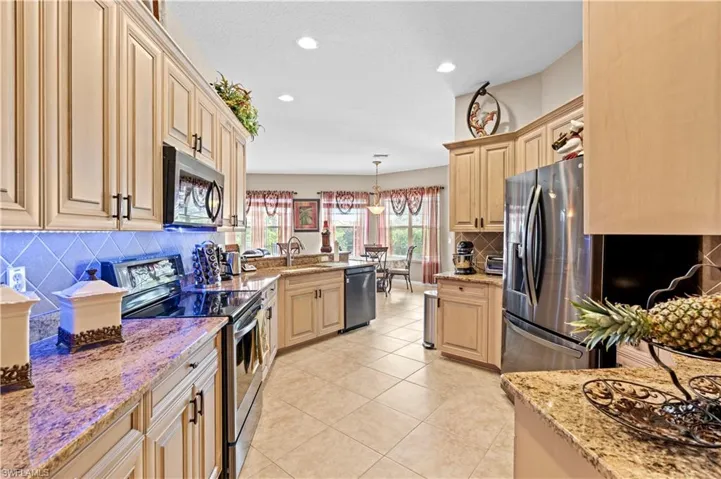 Kitchen featuring decorative backsplash, appliances with stainless steel finishes, light stone counters, and pendant lighting