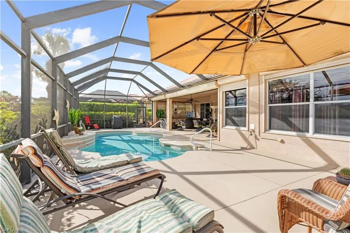 View of pool with glass enclosure, ceiling fan, and a patio