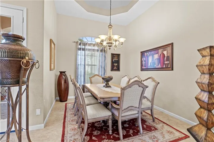 Tiled dining area with a tray ceiling and a chandelier