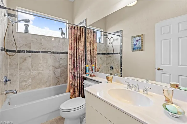 Full bathroom with toilet, vanity, and shower / bath combination with curtain