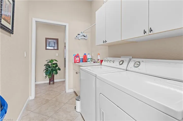 Washroom featuring light tile patterned floors, cabinets, washer and clothes dryer, and sink