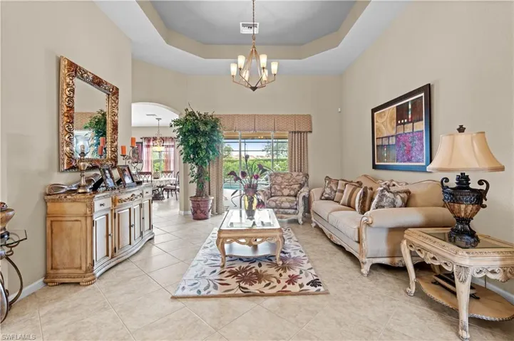 Tiled living room with a raised ceiling and a chandelier