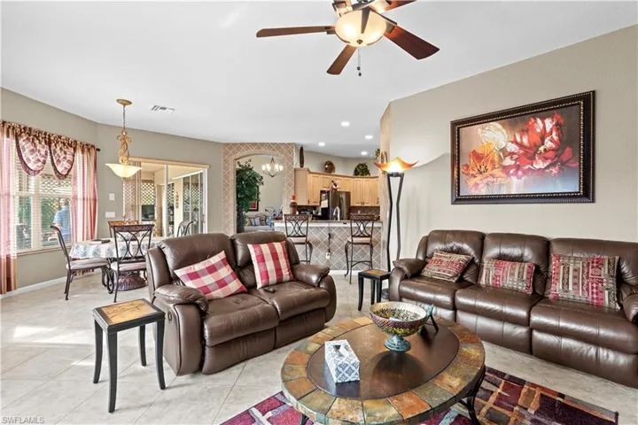Tiled living room with ceiling fan with notable chandelier