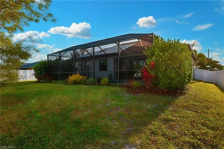 Back of house with a lawn and sc enclosure