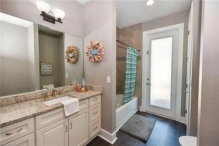 Full bathroom featuring shower / tub combo with curtain, vanity, toilet, and hardwood / wood-style floors