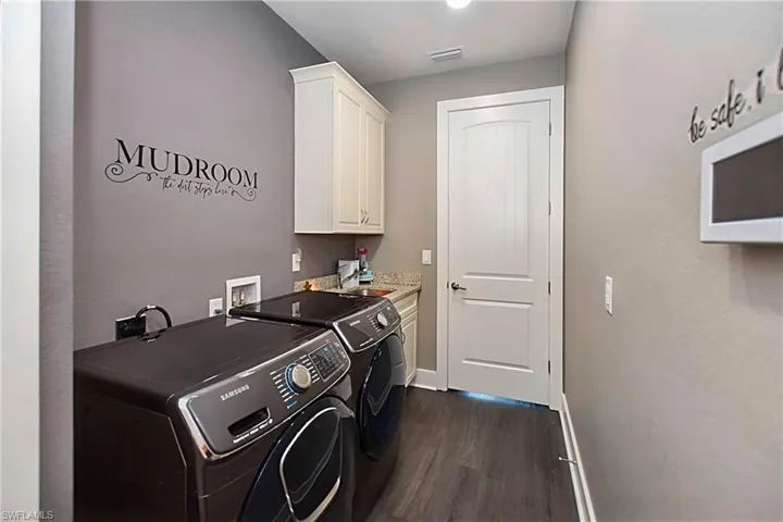 Laundry area featuring sink, cabinets, washer and dryer, and dark hardwood / wood-style floors