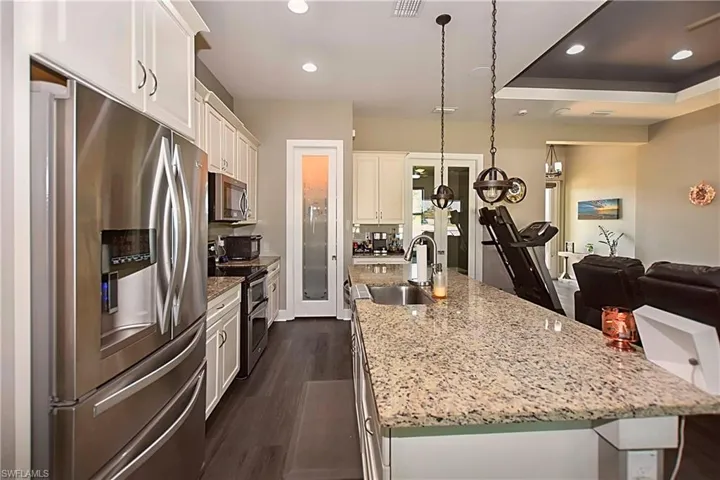 Kitchen with white cabinets, stainless steel appliances, sink, an island with sink, and dark hardwood / wood-style flooring