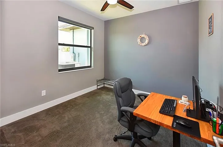 Office space featuring dark colored carpet and ceiling fan