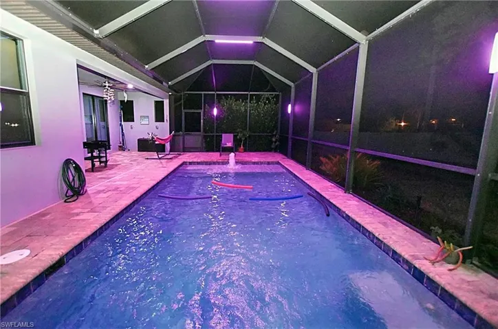 View of swimming pool at night with ceiling fan