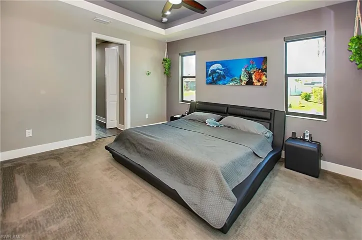 Carpeted bedroom with ceiling fan and a raised ceiling