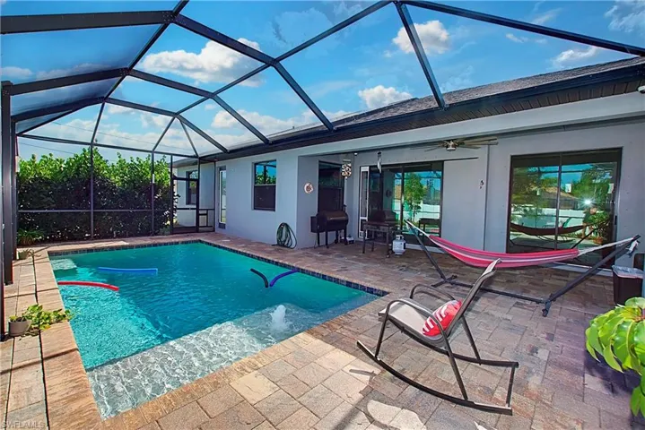 View of swimming pool featuring a lanai, a patio area, and ceiling fan