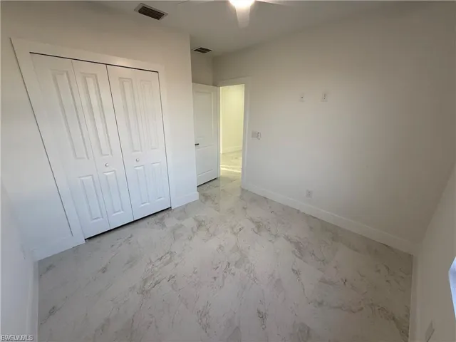 Unfurnished bedroom featuring a closet, a ceiling fan, and light marble finish floors