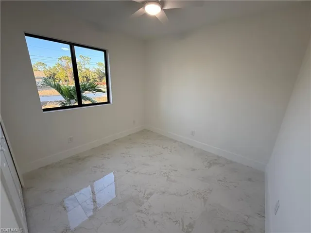 Spare room featuring light marble finish flooring and a ceiling fan