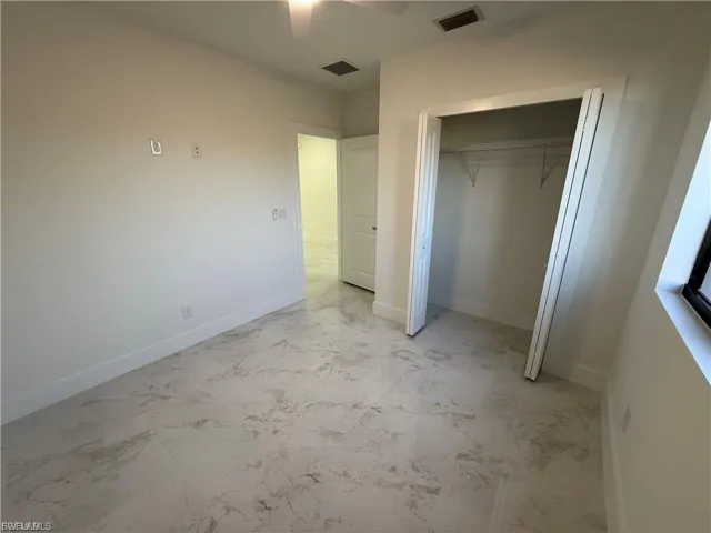 Unfurnished bedroom with light marble finish floors, ceiling fan, and a closet