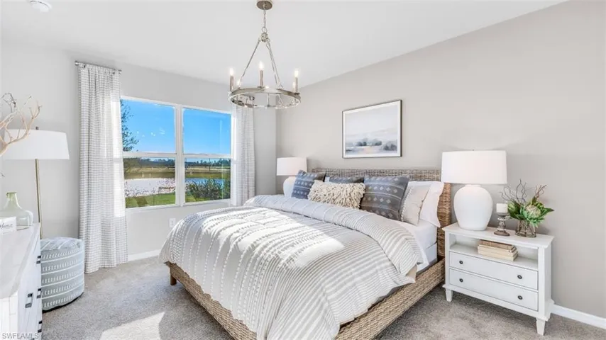 Model home. Bedroom with light colored carpet, a water view, and suspended lighting