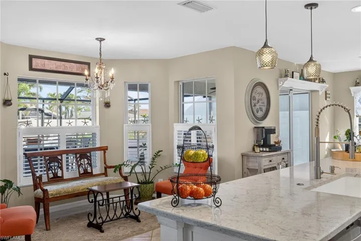 Kitchen with light stone countertops, plenty of natural light, and a chandelier