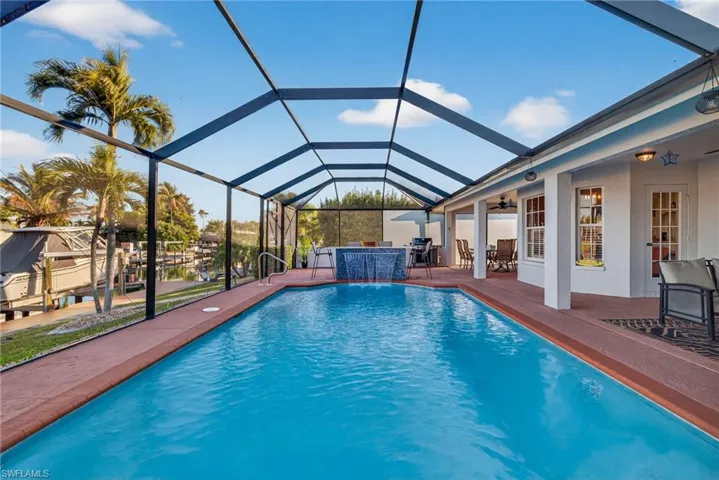 Swimming pool with a sunroom, a lanai, a patio, and an outdoor bar and dining area