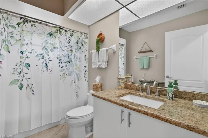 Bathroom featuring vanity, light tile patterned floors, and shower / bath combo with shower curtain