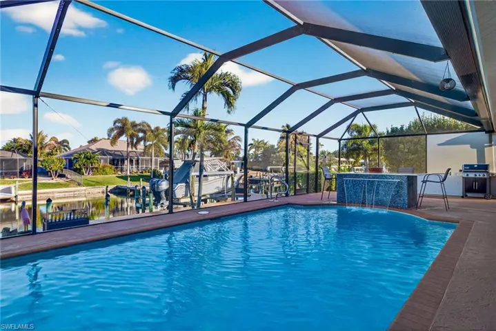 Outdoor pool with a sunroom, boat lift, glass enclosure, a boat dock, and area for grilling
