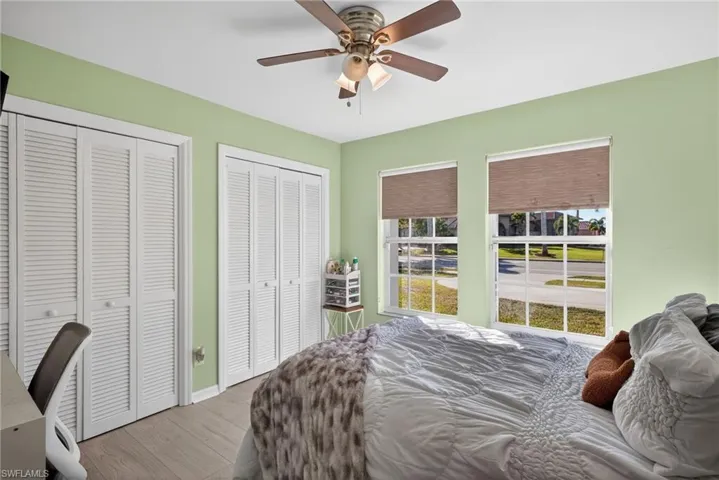Bedroom with multiple closets, wood finished floors, and ceiling fan