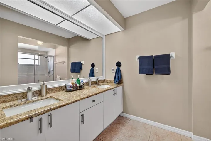 Full bathroom with a shower stall, double vanity, and light tile patterned floors
