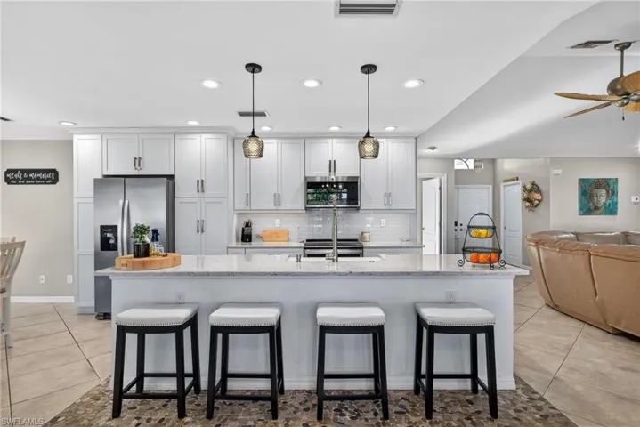 Kitchen with light stone countertops, open floor plan, light tile patterned floors, and a breakfast bar