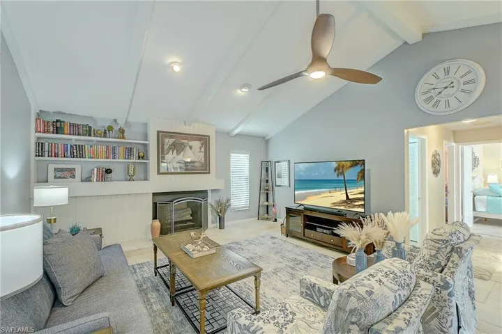 Living area with beamed ceiling, a glass covered fireplace, and high vaulted ceiling