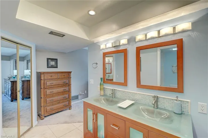 Full bath featuring double vanity, light carpet, tasteful backsplash, and recessed lighting
