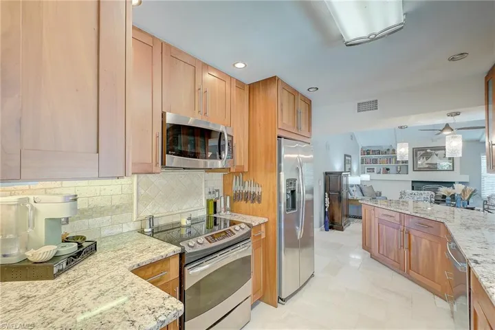 Kitchen with stainless steel appliances, light stone counters, hanging light fixtures, recessed lighting, and backsplash