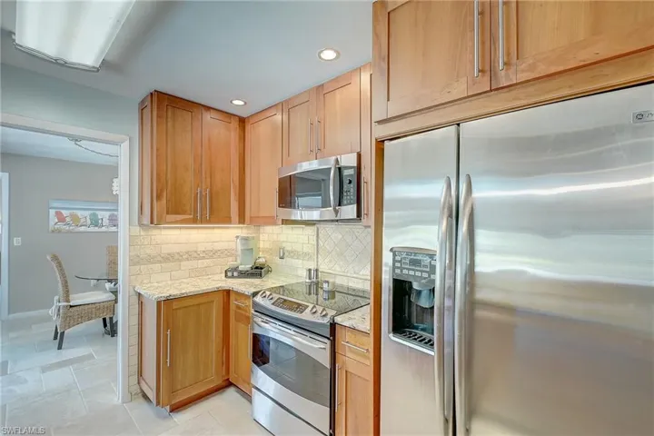 Kitchen with appliances with stainless steel finishes, light stone countertops, recessed lighting, and decorative backsplash
