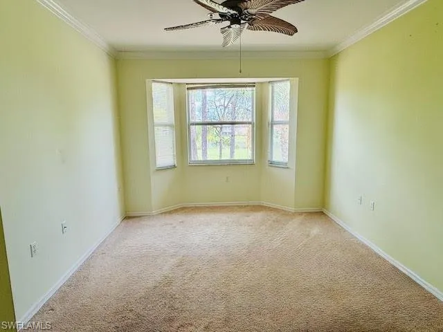 Unfurnished room featuring carpet, ornamental molding, and ceiling fan