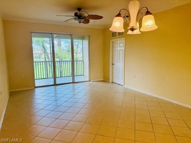 Spare room featuring ornamental molding, light tile patterned flooring, ceiling fan, and a chandelier