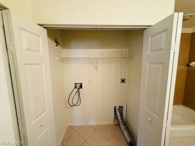 Laundry area featuring light tile patterned floors, hookup for a washing machine, and electric dryer hookup