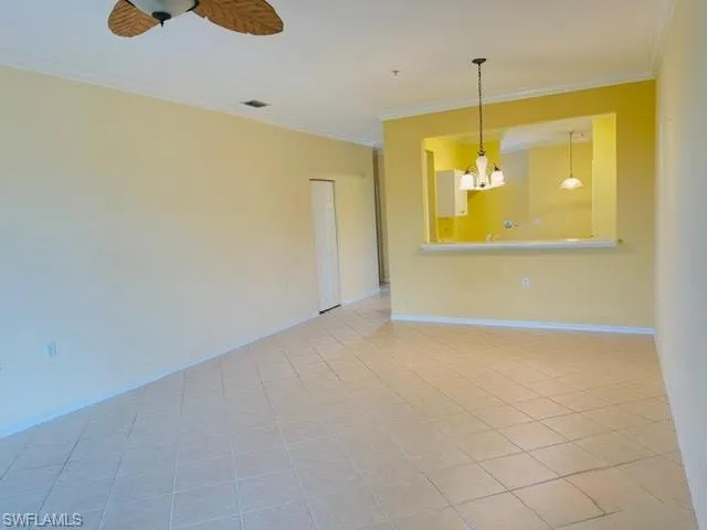 Spare room with ornamental molding, a chandelier, light tile patterned floors, and ceiling fan