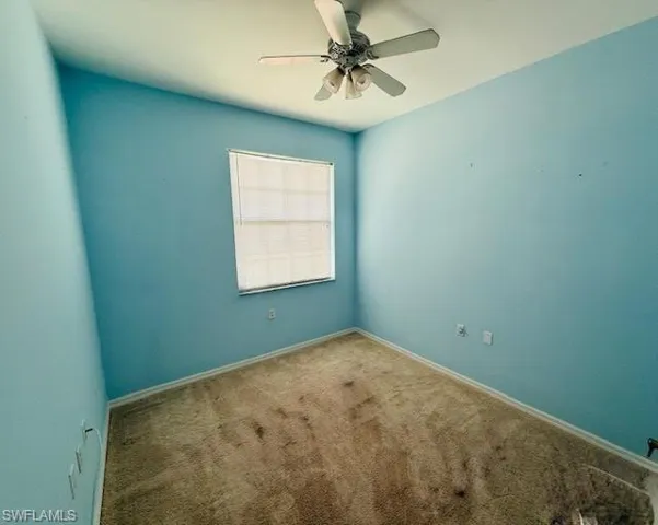 Spare room featuring carpet and ceiling fan
