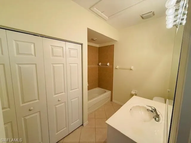 Full bath with light tile patterned flooring, a closet, vanity, and shower / tub combination