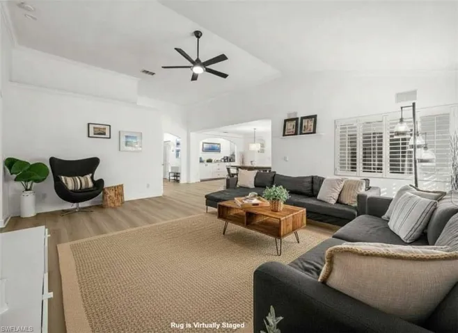 Living room featuring wood finished floors, vaulted ceiling, and ceiling fan