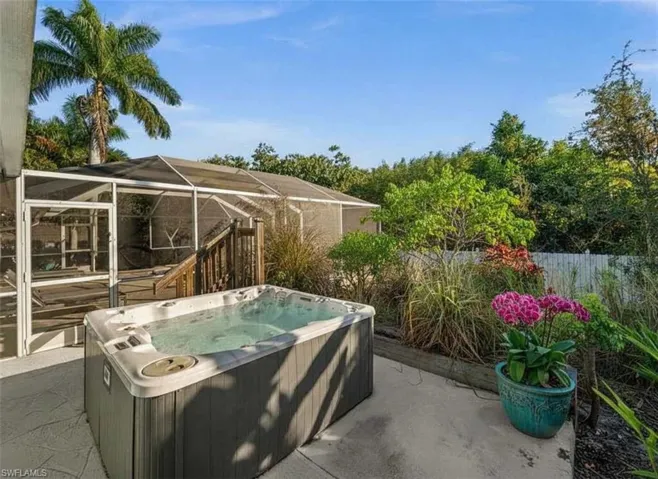View of patio featuring a lanai, a sunroom, and a hot tub