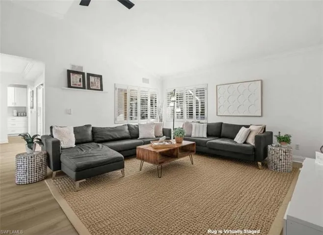Living area featuring light wood-style floors, ornamental molding, and vaulted ceiling