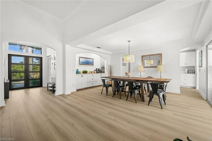 Dining room featuring arched walkways, plenty of natural light, crown molding, light wood-style floors, and a high ceiling