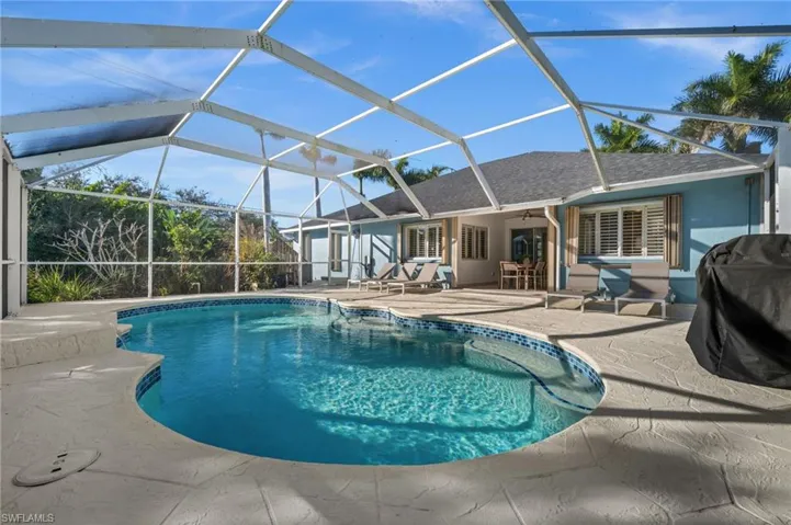 Outdoor pool featuring a sunroom, a patio, glass enclosure, and area for grilling