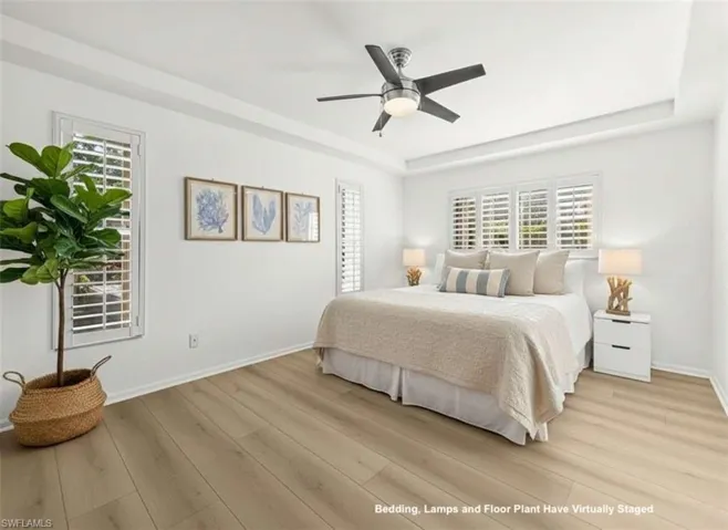 Bedroom featuring a raised ceiling, a ceiling fan, and light wood-type flooring