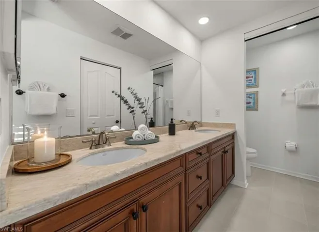Bathroom with double vanity, curtained shower, light tile patterned floors, and recessed lighting